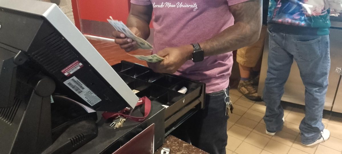 An employee in the bookstore counting money as students buy the things they "need."