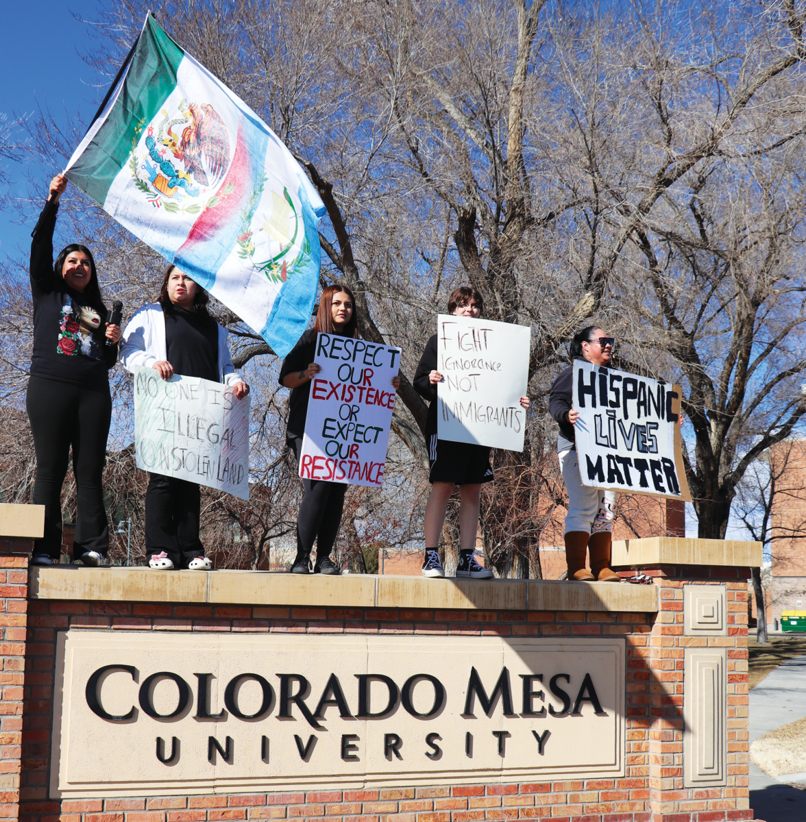 A group of protestors consisting of CMU students, alumni and Grand Junction locals stand together flying signs and flags. Protests have been taking place near campus every weekend from 10a.m. to 3p.m.