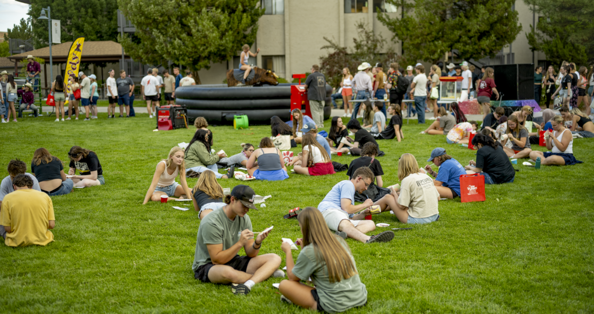 Students partake in pottery painting amidst the bustle of other activities.