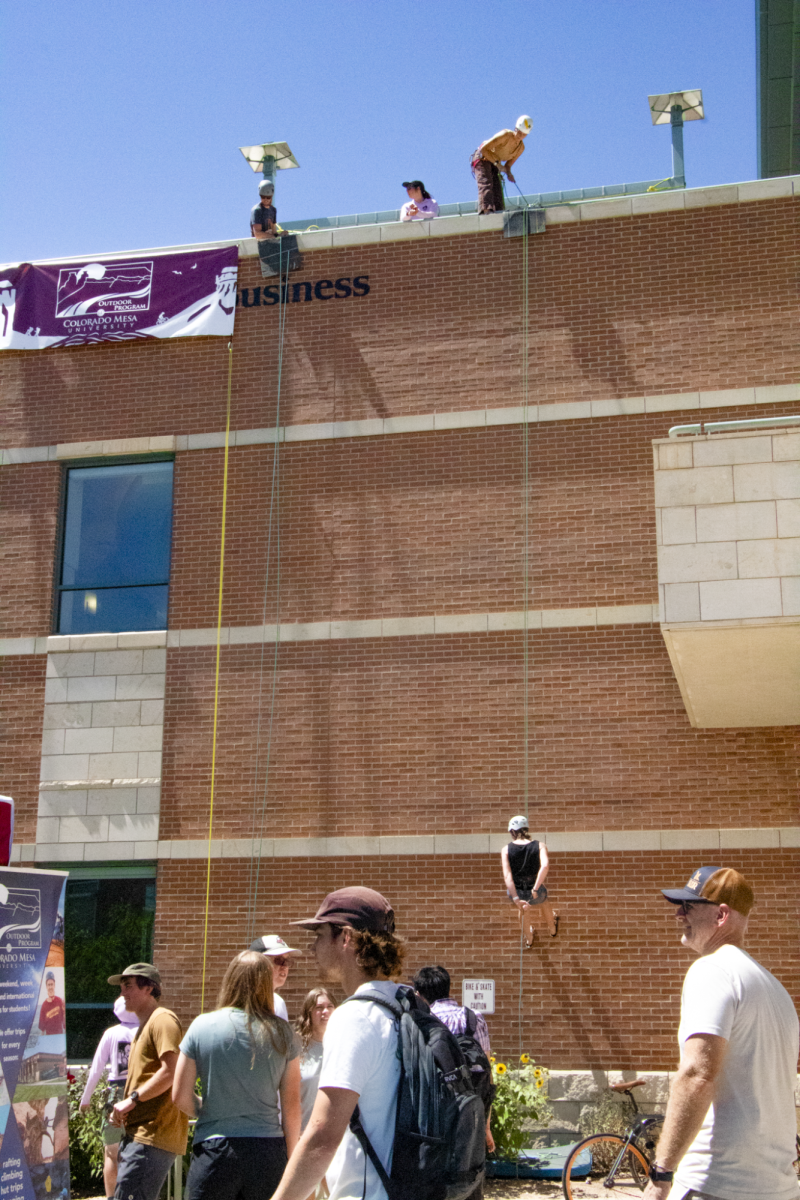 Students repelling down the side of the Davis School of Business. The Outdoor Program hosts various outdoor activities accessible to students. 