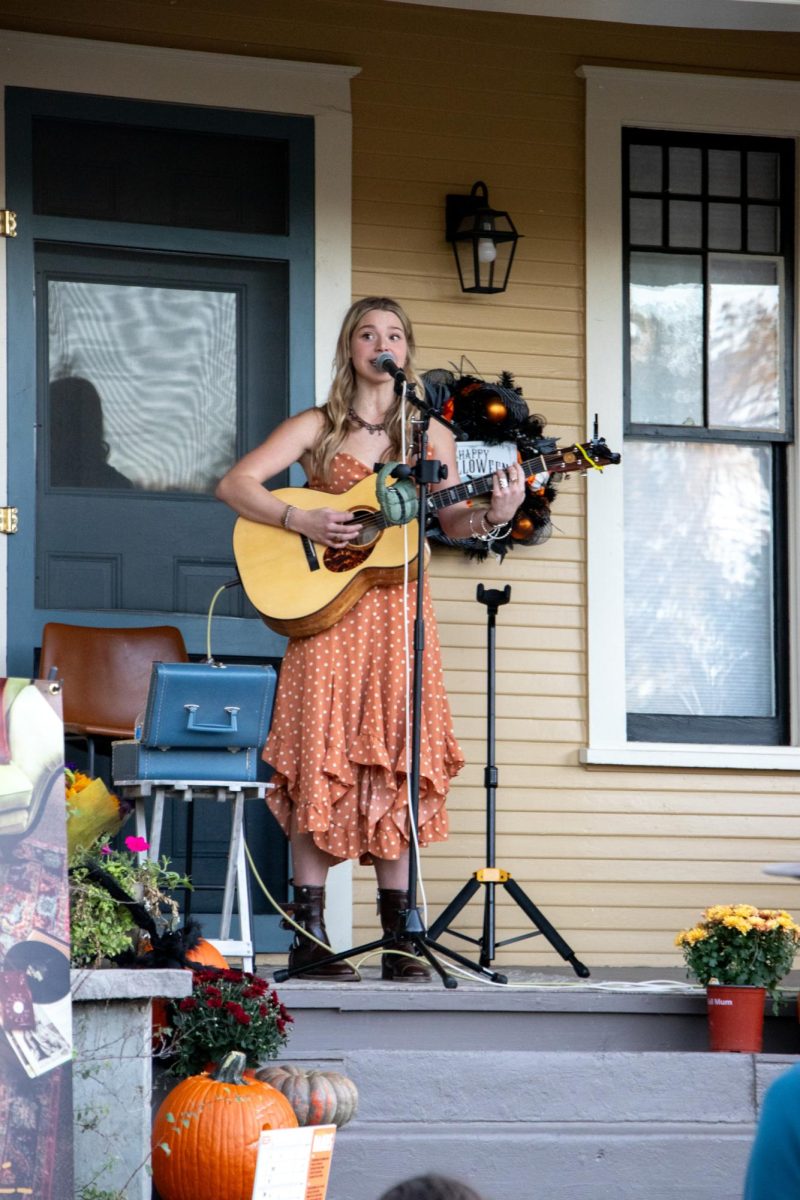 CMU alum Izzy Burns sings to an audience from the porch of a home in Grand Junction's historic downtown neighborhood. Many other artists performed in the area as well.