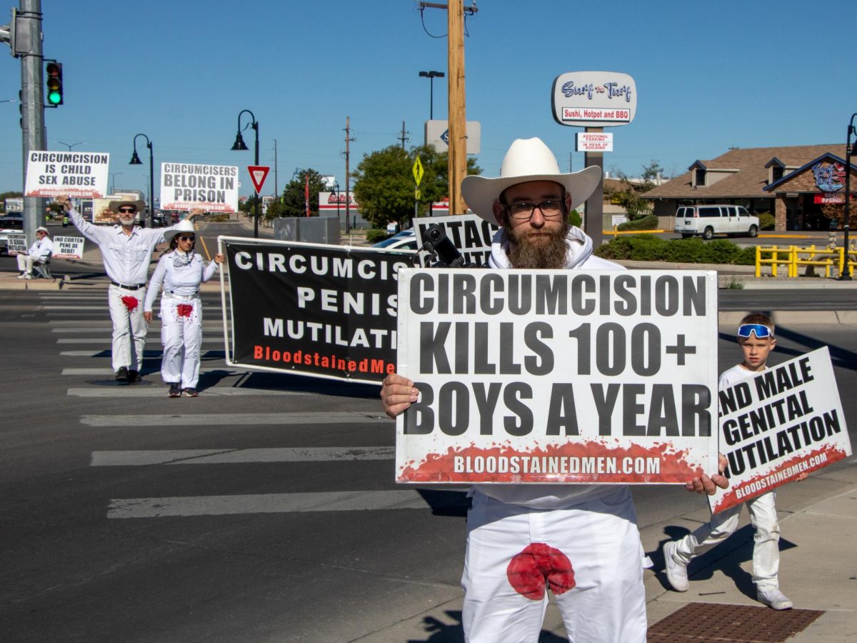 Protester and acting driver, manager and press spokesperson for The Bloodstained Men Mathew Kinnison walks on Independent Avenue and US Highway 6 and 50, holding up a sign that reads: “Circumcision Kills 100+ Boys A Year” and the web address for The Bloodstained Men’s website. The website expresses the group’s views on circumcision.
