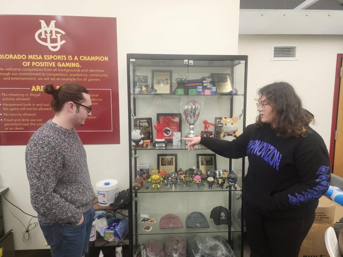 CMU Competitive E-Sports team captain Lindsey Chaskelis and fifth year accounting major Everett Rogers point out the trophy their team secured at the Rocky Mountain Collegiate Series LAN tournament on Nov. 16. The team, nicknamed The Stegos and Toads, competed with other colleges for first place across Overwatch 2 and Super Smash Bros. Ultimate matches.