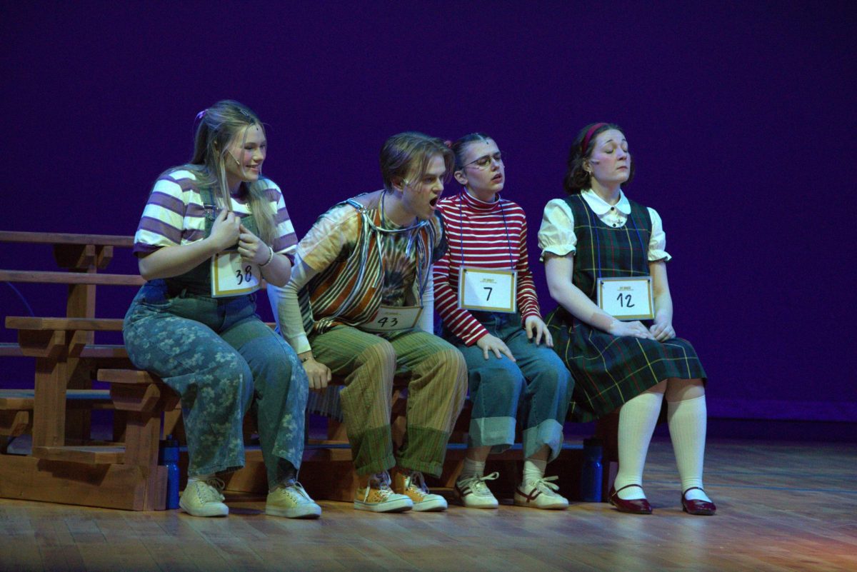 Annalyn Milford as Olive Ostrovky, Levi Hughes as Leaf Coneybear, Lucy Amann as Logainne Schwartzandgrubennire, and Abigail Smith as Macy Park listen to Garrison T. Herbert spell as William Barfee. Photo taken February 23rd, 2026.