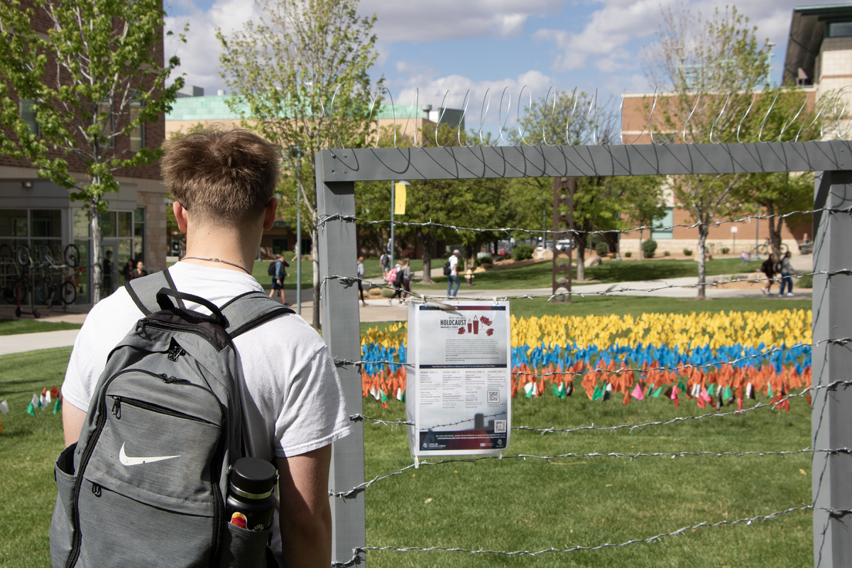 A student reading the information flyer hung to barbed wire for the 23rd Holocaust Awareness Series. The sign is in front of the Field of Flags which is built each year as a memorial to the lives lost during the Holocaust. Each flag represents 5,000 individual lives lost.